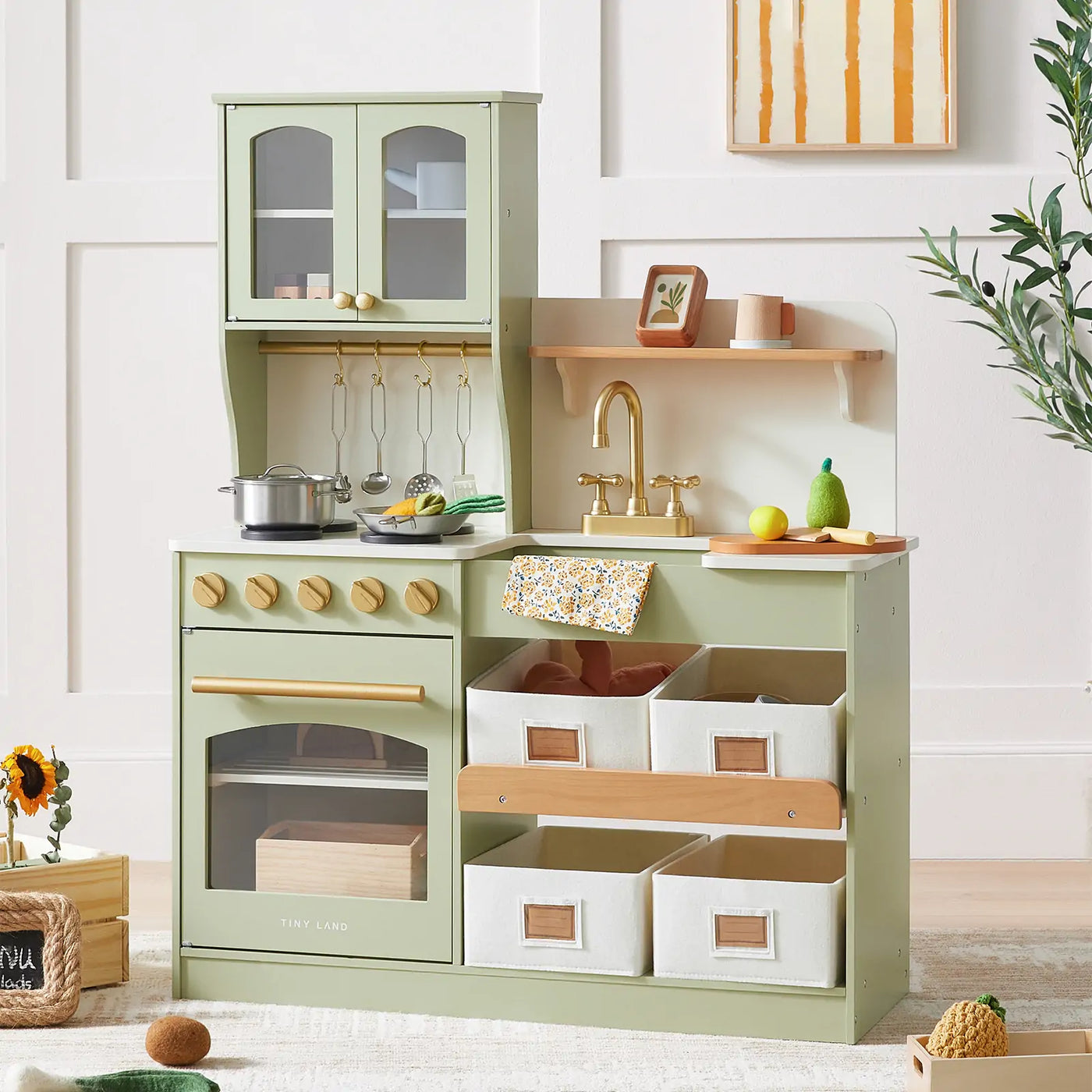 The Tiny Land® Pretend Play Kitchen for Toddlers - Serenity Wooden Kitchen in green features gold accents, shelves, hooks with pretend cookware, a toy stove, sink, oven, and storage bins—perfect for imaginative play.