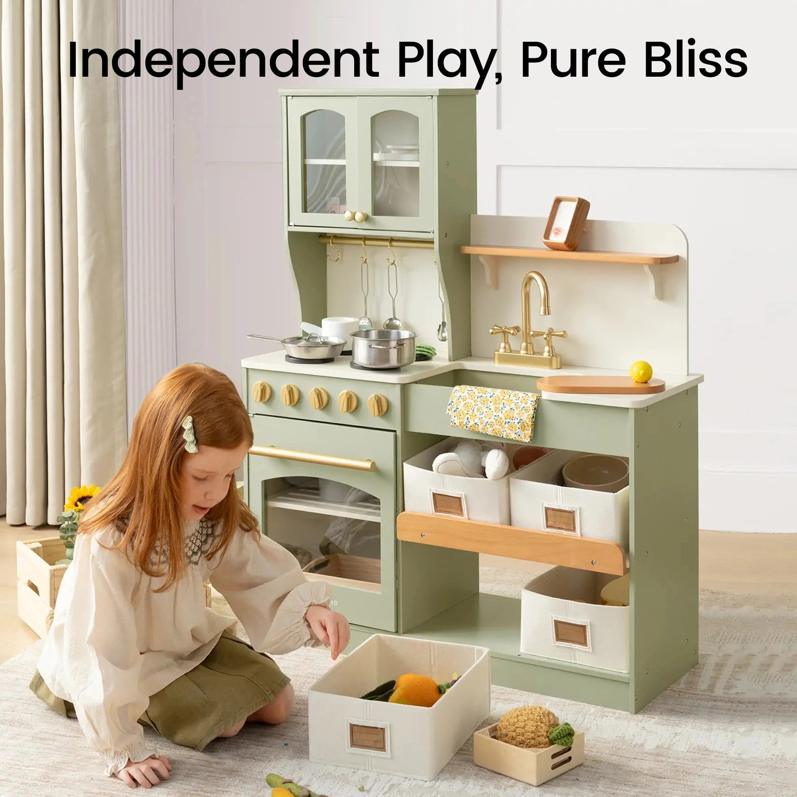 A young girl enjoys imaginative play with the Tiny Land® Wooden Play Kitchen with Storage for Creative Toddlers by Tiny Land, surrounded by organized storage bins and a variety of toy food. The text above reads, "Independent Play, Pure Bliss." Colorful curtains frame the scene as she stirs up make-believe meals using pretend cookware.|sage
