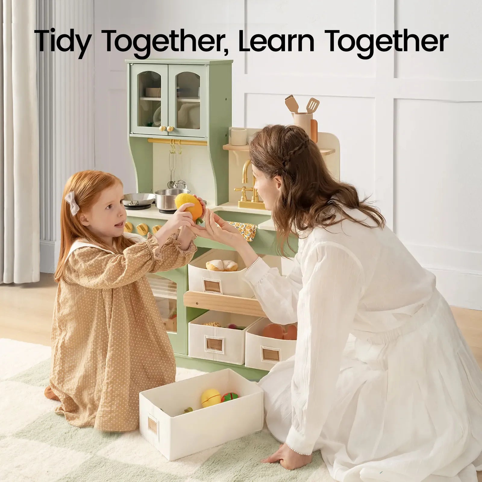A woman and a young girl organize toy food in the Tiny Land® Wooden Play Kitchen with Storage for Creative Toddlers. Text above reads, Tidy Together, Learn Together. Both are smiling and interacting on a light rug in a bright room, enjoying imaginative play with their pretend cookware from Tiny Land.|sage