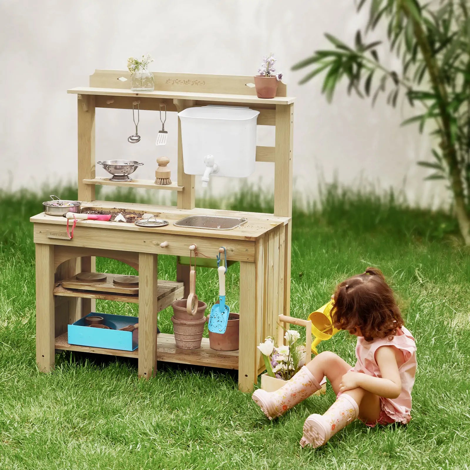 Little girl gardening next to Tiny Land® DuoPlay Mud Kitchen outdoor playset