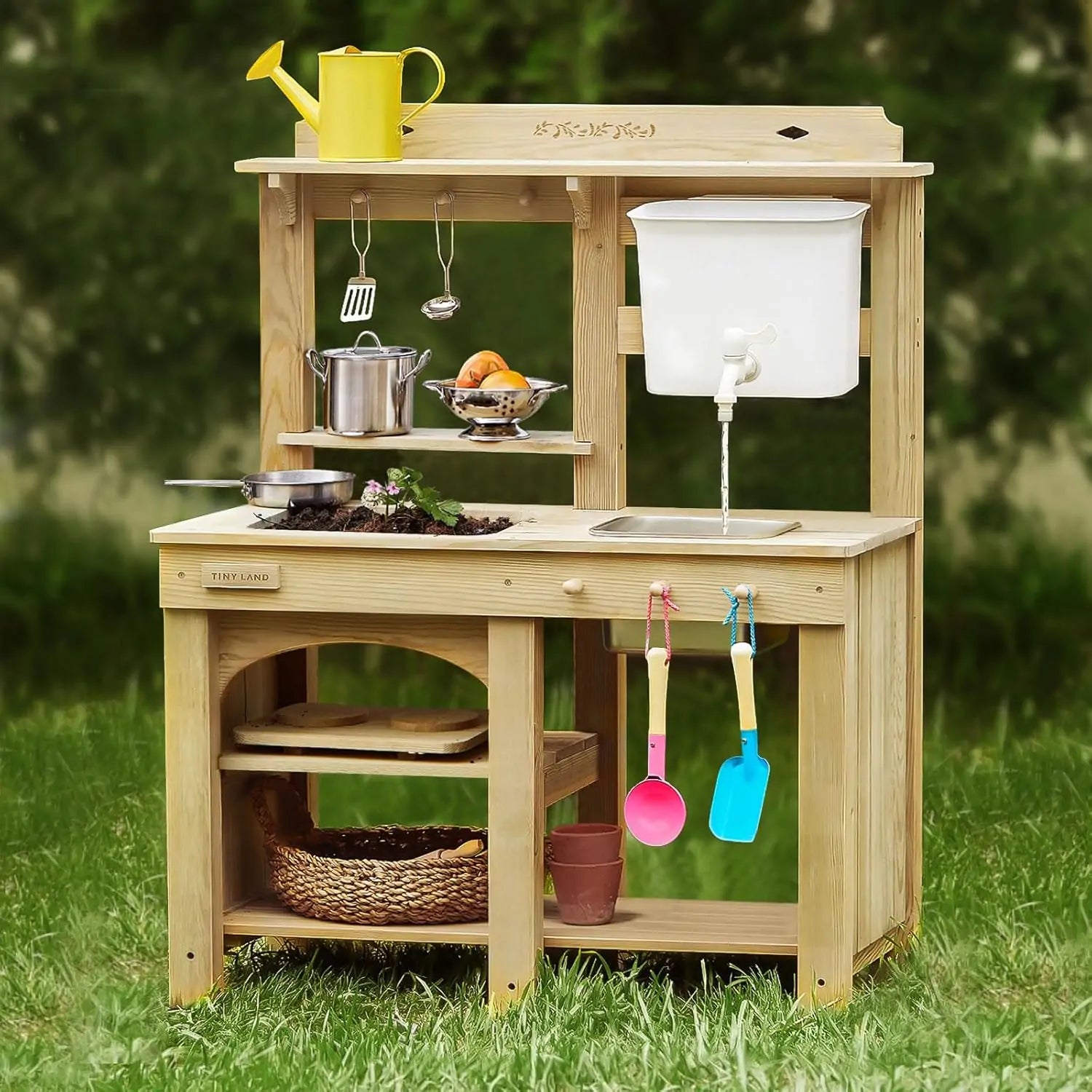 The Tiny Land® Mud Kitchen - DuoPlay Outdoor Play Kitchen for Kids by Tiny Land features shelves, a faucet, toy utensils, play food, and colorful scoops—plus a yellow watering can—perfect for sensory and outdoor adventures on the lawn.