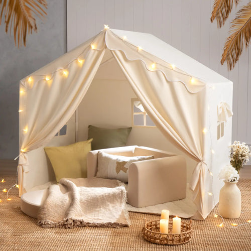 The Tiny Land® Kids Tent – Large Cozy Tent with Star Lights by Tiny Land features soft pillows, a blanket, and a small sofa on a woven rug, creating a warm, inviting atmosphere perfect for kids to play and relax.