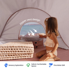A young girl in a striped swimsuit sits inside the Tiny Land® One-Stop Beach Toy & Tent Set by the shore, with an open zipper vent for airflow. Folded mats and icons highlight sensory exploration, UV protection, safety, and support for fine motor skills.|Blush Pink