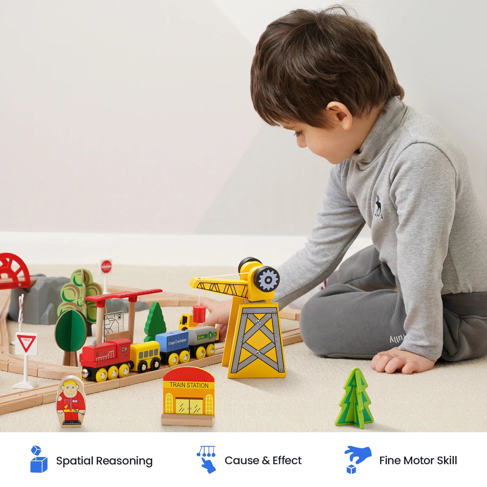 A young child sits on the floor playing with the Tiny Land® Wooden Train Set for Children by Tiny Land, crafted from sustainable wood. Icons and text below highlight benefits: Spatial Reasoning, Cause & Effect, and Fine Motor Skills. This train set is also compatible with popular wooden railway brands, providing endless opportunities for creative play.|55 Pcs