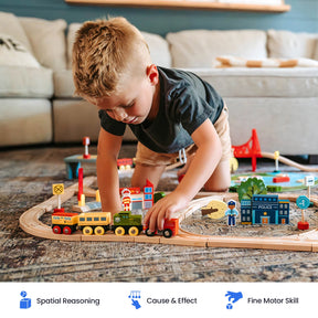A young boy plays with the Tiny Land® Wooden Train Set for Children by Tiny Land on the floor. The sustainable wooden track set includes buildings, signs, and a compatible toy train that works with other popular wooden railway brands. Educational icons below highlight benefits such as spatial reasoning, cause and effect understanding, and fine motor skill development.|110 Pcs