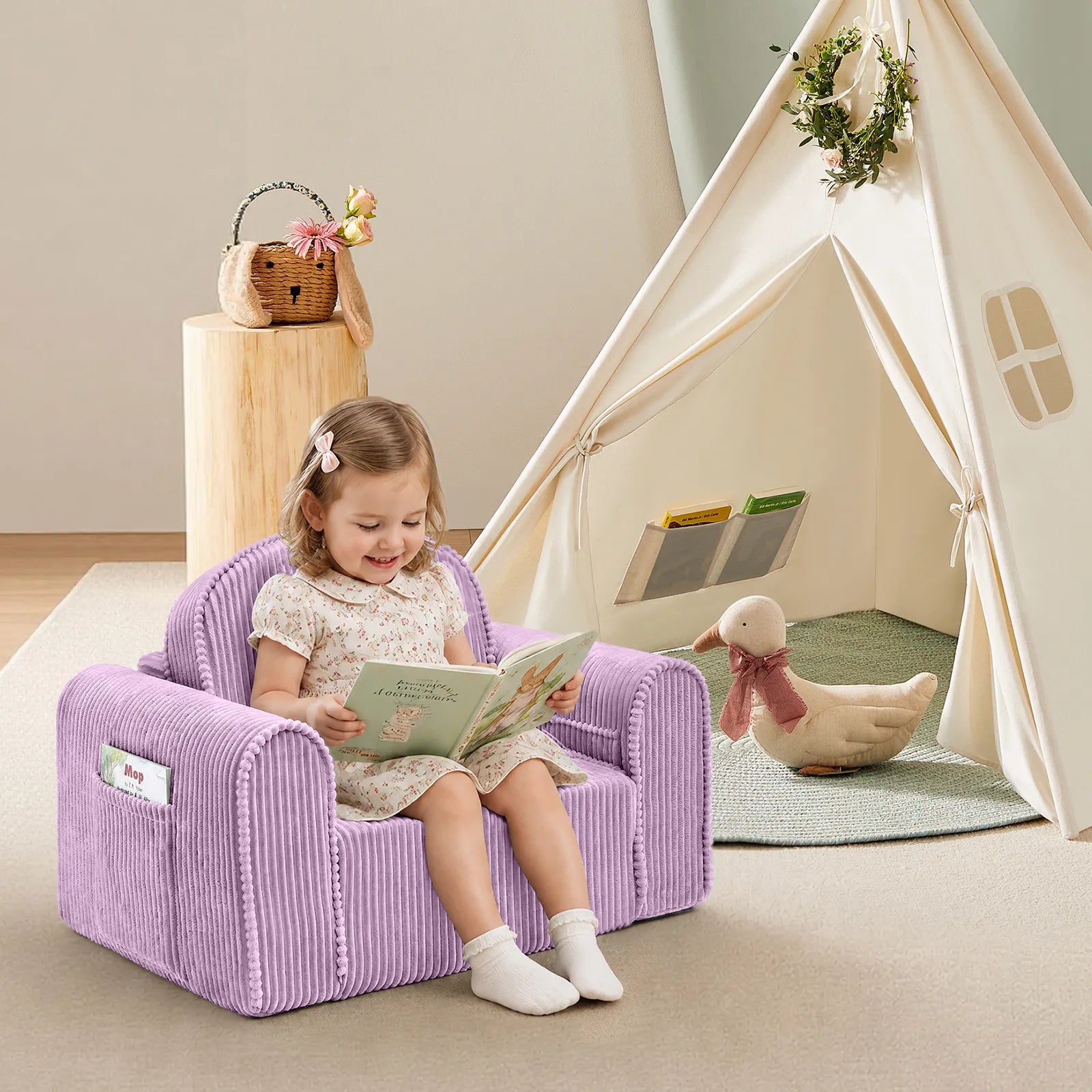 A young child sits on the Tiny Land® Ultimate Reading Retreat Corduroy Lounger, reading a book in a cozy, softly lit room. Nearby, the Premium Teepee from Tiny Land INC serves as an inviting Montessori-inspired kids’ reading nook, accompanied by a stuffed duck with a scarf and a basket on a small wooden table.|Purple