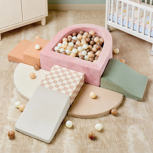 The Tiny Land® PlayNest Climbing Ball Pit Set with Tunnel is a pastel indoor playground for toddlers, featuring soft climbing blocks, ramps, and a pink foam ball pit filled with beige, white, and brown balls.