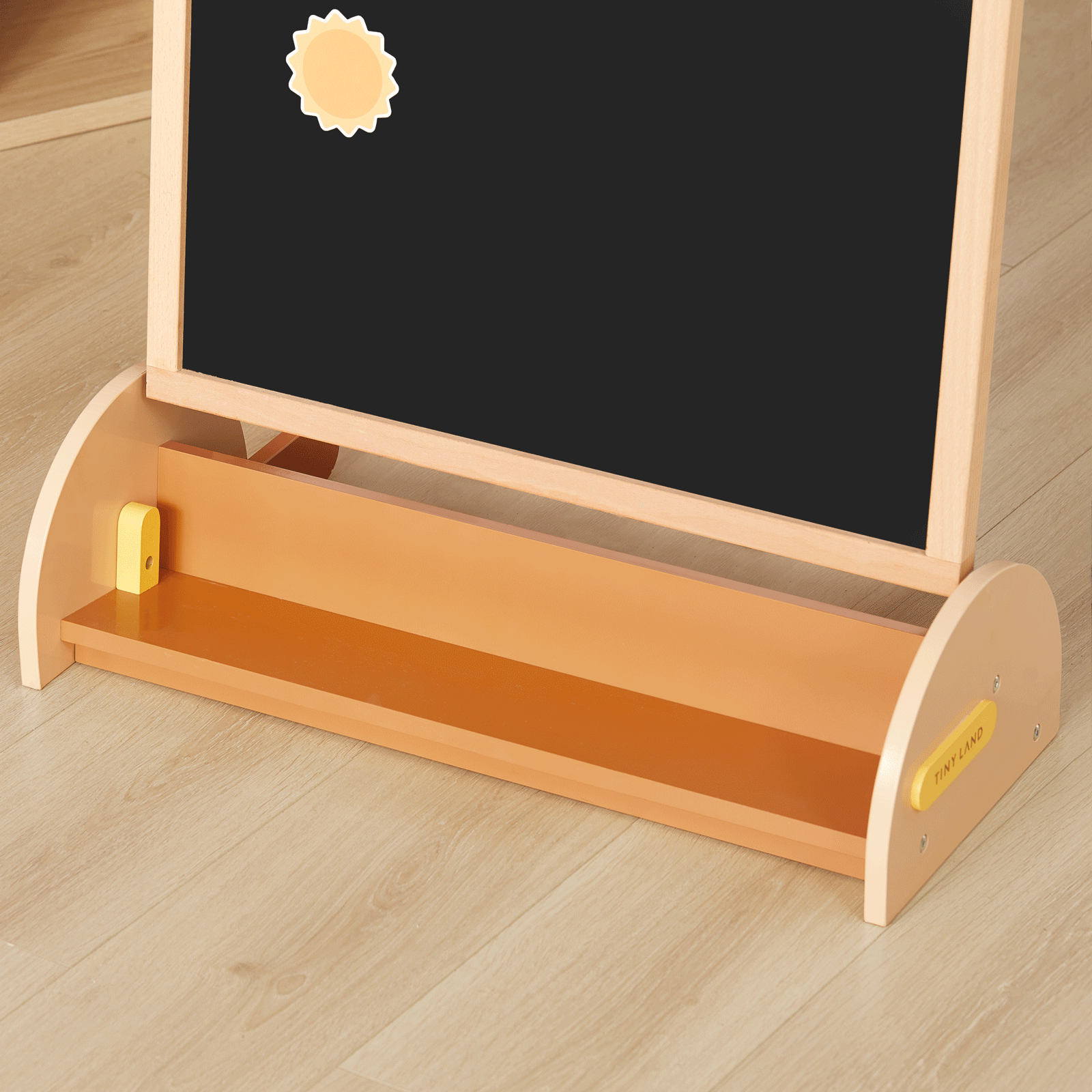 The Tiny Land® Double-Sided Arched Magnet Chalkboard by Tiny Land features a black chalkboard with a sun-shaped magnet, a light brown wooden tray, and stands on a light wood floor—perfect for creative play and learning.
