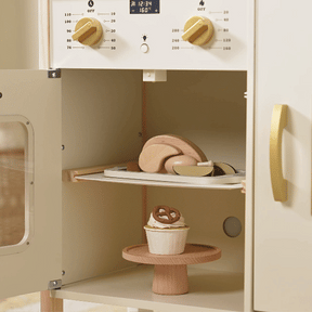 The Tiny Land® PopJoy Kitchen & Fridge Set features an open toy oven displaying wooden play food—a cupcake with a pretzel on the bottom shelf and a roast with veggies on the middle tray—perfect for pretend play.