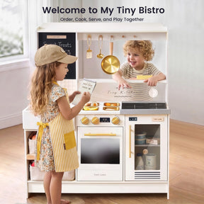 Two young children engage in imaginative play with the Tiny Land® BistroSwitch Play Kitchen by Tiny Land—one child, wearing a cap and apron, takes an order while the other sits behind the counter, smiling as they “cook.”.