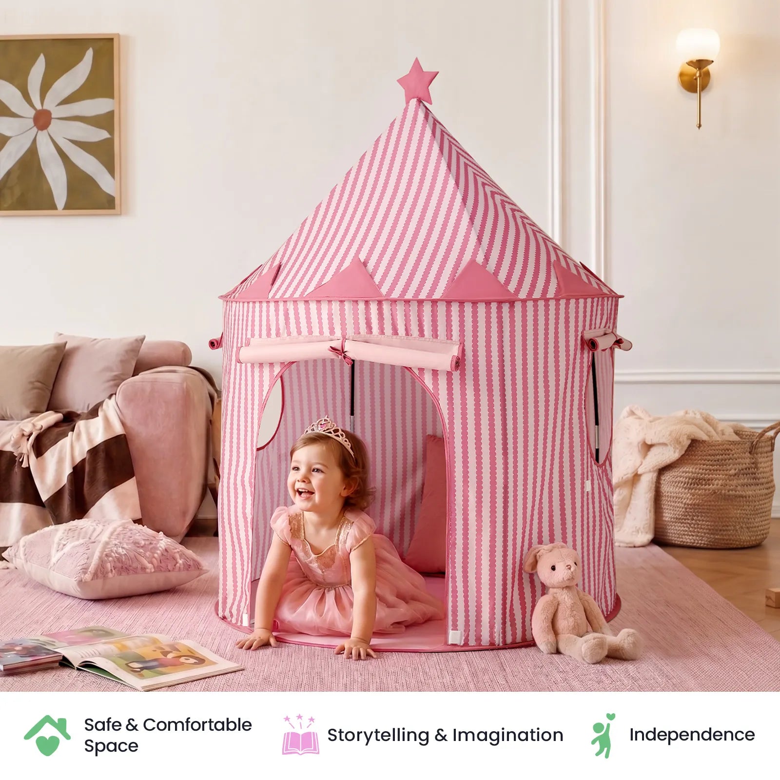 A smiling toddler in a pink dress crawls out of the Tiny Land® Kids Tent – Indoor Tent for Toddlers by Tiny Land in a cozy room, surrounded by a teddy bear, a pink rug, and wall art. Icons and text about the tent’s benefits appear at the bottom.|Pink
