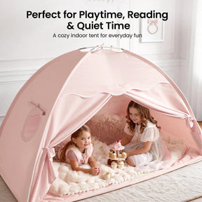 Two young girls in white dresses smile inside the Tiny Land® Kids Bed Tent, a cozy hideaway by Tiny Land. The light pink tent, decorated with plush rugs and toy cupcakes, is set up in a bright, elegant room with framed art on the wall.|Pink