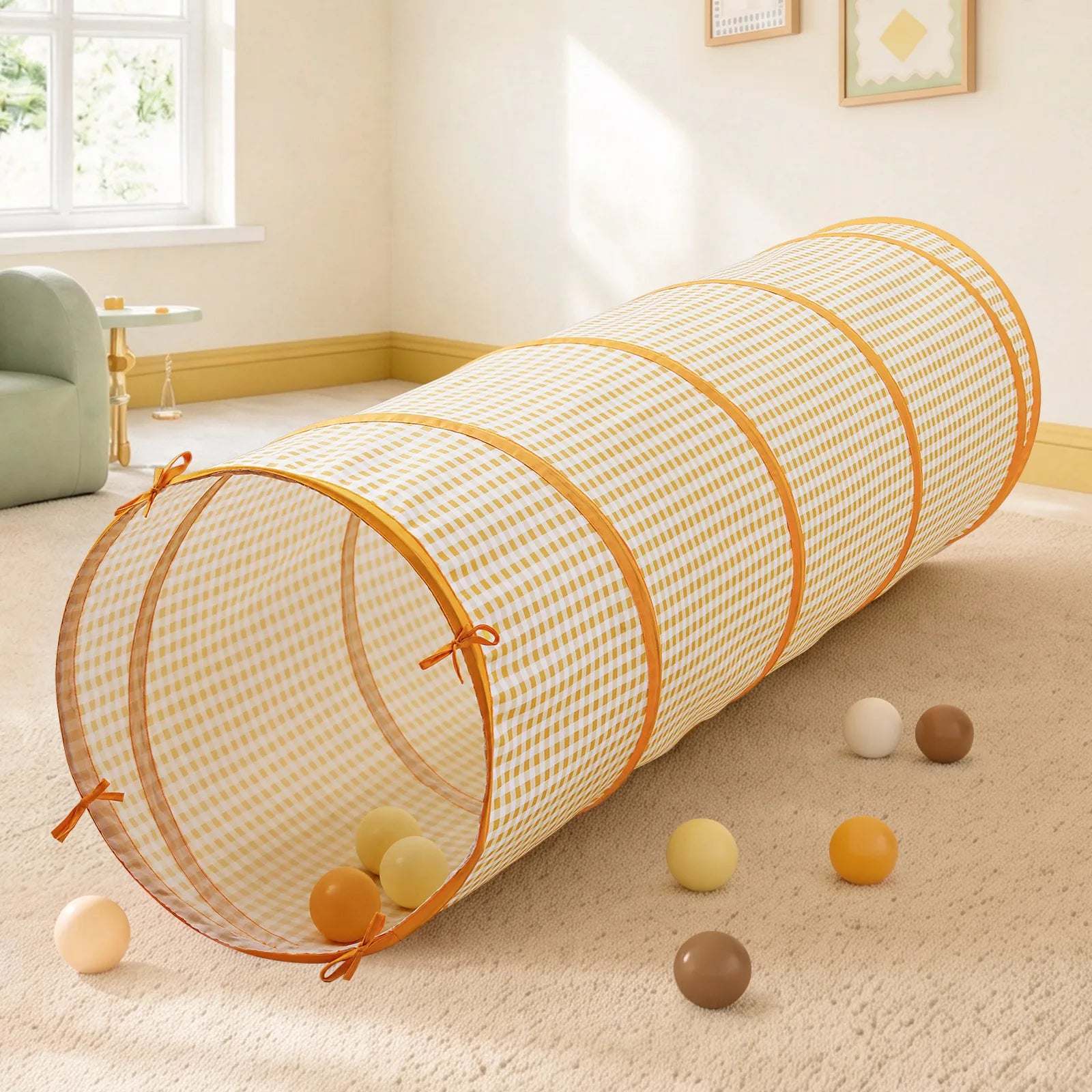 A yellow gingham Tiny Land® Adventure Play Tunnel rests on a carpet scattered with several play balls.|Yellow