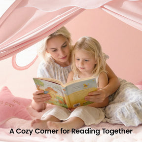 A woman and a young girl read a children’s book together inside the Tiny Land® Kids Bed Tent by Tiny Land. Surrounded by soft pink pillows, they enjoy a cozy kids hideaway. Text reads: A Cozy Corner for Reading Together.|Pink