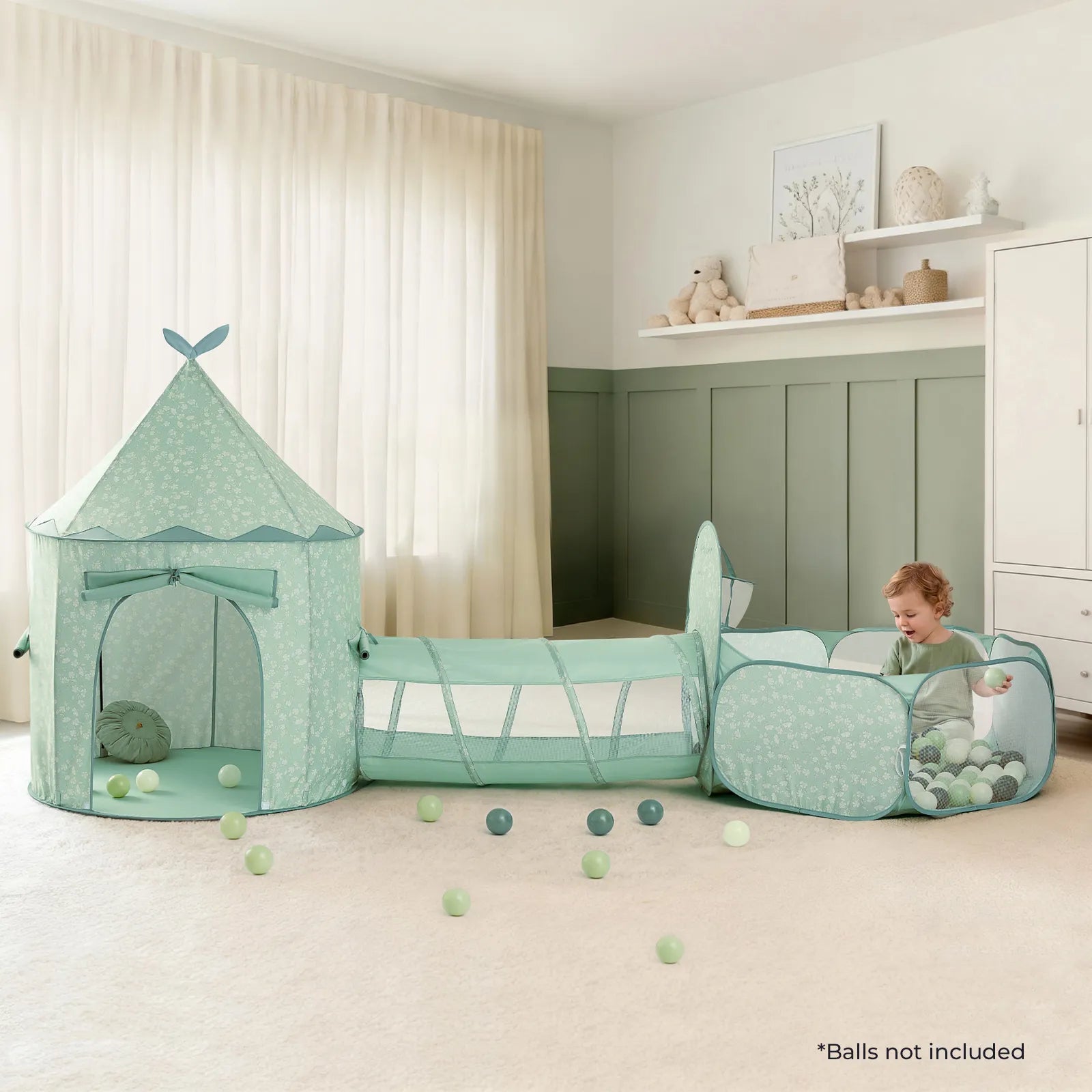 A baby plays in a pastel green Tiny Land® Compact Adventure 3-in-1 Play Tunnel, which includes a matching play tent and connecting tunnel, in a softly lit, cozy nursery. Colorful balls are scattered on the floor (not included with the product), while charming shelves and decor complete the inviting background.|green