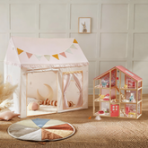 A cozy playroom showcases the Tiny Land Sweet Dreams Playset—featuring a pink-white playhouse and a pink dollhouse—set on a round rug, inspiring imaginative play against a white panel wall.