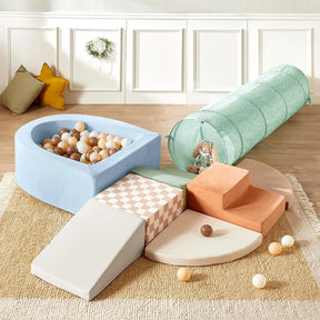 The Tiny Land® PlayNest Climbing Ball Pit Set with Tunnel by Tiny Land features a pastel indoor playground with a foam ball pit, soft steps, climbing blocks, slide, and mint green tunnel on a beige rug. Neutral balls and pillows decorate the background.