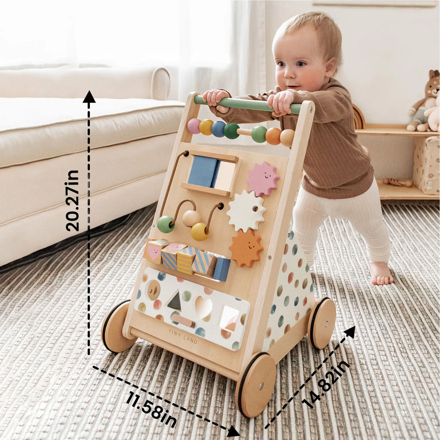 A baby pushes the Tiny Land® Versatile Natural Wooden Baby Walker by Tiny Land—with its colorful beads and shapes—across a carpeted floor in a cozy living room. The walker measures 20.27 inches tall, 11.58 inches wide, and 14.82 inches deep.