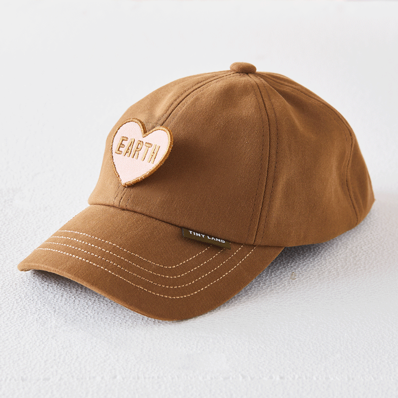 A brown baseball cap with a heart “EARTH” patch and a small TINY LAND tag, perfect as an accessory for the Tiny Land® BistroSwitch Play Kitchen or for pretend play. Shown on a light textured surface.|Green