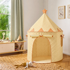The Tiny Land® Kids Tent from Tiny Land INC features a yellow and white checkered design with a star on top, set on a woven rug in a bright room. A stuffed bunny sits in front, with a window, bookshelf, and animal art in the background.