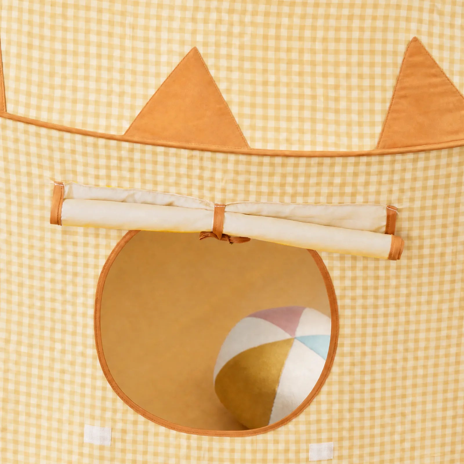 A close-up of the Tiny Land® Kids Tent by Tiny Land INC shows a yellow gingham indoor tent for toddlers with two triangular peaks, a rolled-up window flap, and a round opening revealing a colorful patchwork ball inside.