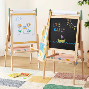 Two Tiny Land® 3-in-1 Art Easels for Kids by Tiny Land stand side by side; one displays a drawing of flowers, while the other features “123 SAIL” and a boat on the chalkboard. Art supplies are organized on shelves beneath the adjustable easel, with a colorful rug and books placed on the floor nearby.|green